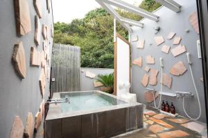 a bathroom with a hot tub and a shower at Beach Side Inn Shirahama in Shimoda