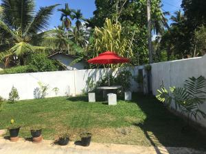 a table with a red umbrella in a yard at Villa N in Unawatuna