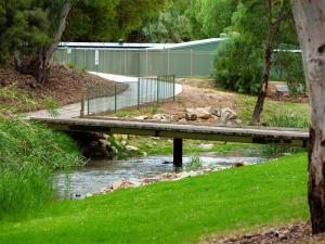 a wooden bridge over a river with a fence at Windsor Gardens Caravan Park in Adelaide