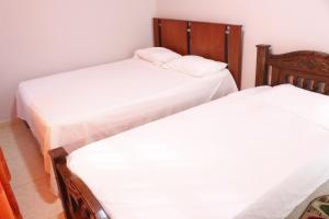 Habitación con 2 camas individuales y sábanas blancas. en Apartamentos Arpushana, en Ríohacha