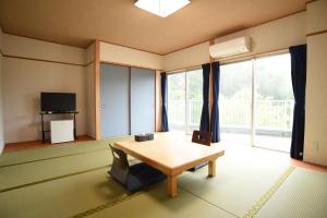 a living room with a table and a large window at Alaise De Bale Shirahama in Shirahama