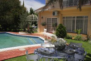 a table and chairs in a yard next to a pool at A Summer Place Boutique Guest House in Bloemfontein