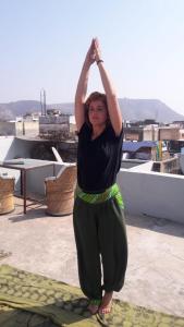 uma mulher a fazer uma pose de yoga no telhado em Bhavyam HomeStay &Cafe BackPackers ko em Bundi