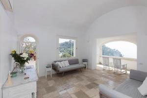 a living room with a couch and two windows at Casa Capaianca in Capri
