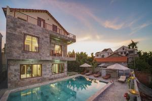 a house with a swimming pool next to a building at Herbal Tea Homestay in Hoi An