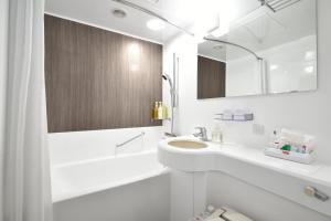 a white bathroom with a sink and a mirror at Kichijoji Tokyu REI Hotel in Musashino