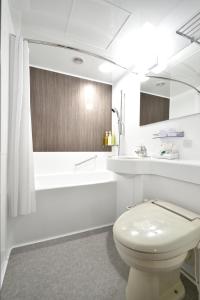 a white bathroom with a toilet and a bath tub at Kichijoji Tokyu REI Hotel in Musashino