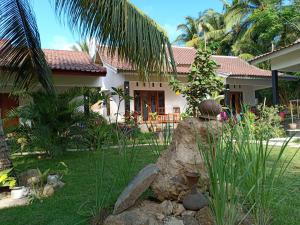 ein Haus mit einem großen Felsen im Hof in der Unterkunft Dewi Garden Guesthouse in Kuta Lombok