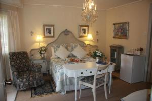 a bedroom with a bed and a table and a chair at A Summer Place Boutique Guest House in Bloemfontein