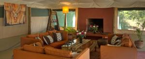 a living room with orange couches and a table at Kicheche Laikipia Camp in Ol Pejeta Conservancy
