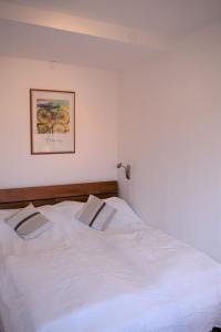 a white bed in a bedroom with a picture on the wall at Haus am Deich Wohnung 10 in Dahme
