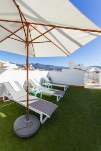 a group of white chairs and an umbrella on the grass at Hotel El Tajo & SPA in Ronda