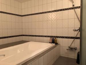 y baño de azulejos blancos con bañera blanca. en Prime Hotel Fulula プライムホテル フルーラ, en Osaka