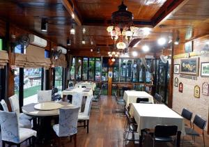 uma sala de jantar com mesas e cadeiras e um lustre em Suwanna Riverside em Chai Nat
