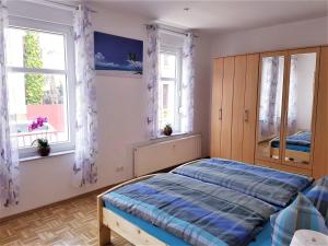 ein Schlafzimmer mit einem Bett und zwei Fenstern in der Unterkunft Ferienwohnung Geratal II in Erfurt