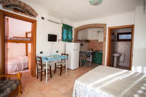 a living room with a table and a kitchen with a refrigerator at Residenza Su Prelau in Gonnesa