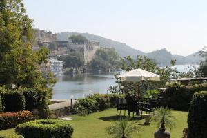 a view of a river with chairs and an umbrella at Karohi Haveli - A Heritage Hotel in Udaipur