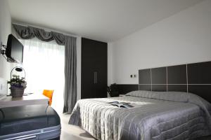 una camera da letto con un letto, un tavolo e una televisione di Hotel Garnì Corallo a Torbole
