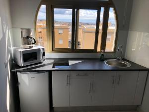 a kitchen with a microwave and a sink and a window at Maravilloso Apart. 8 pax, Tablero 8, Playa Inglés in El Tablero