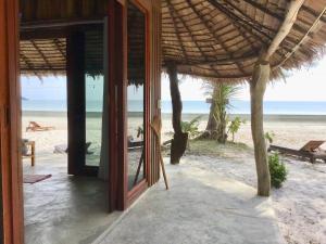 una puerta abierta a una casa de playa con el océano en Ailay, en Ko Phayam