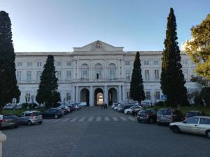 a large white building with cars parked in a parking lot at The Tram 18 Space in Lisbon