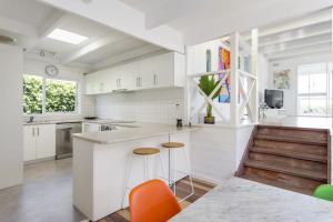 a kitchen with white cabinets and orange chairs at At Agnes Ave: coastal views in Blairgowrie