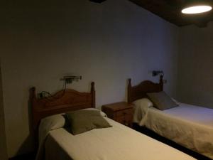 1 dormitorio con 2 camas y 2 luces en la pared en LA ANTIGUA TAHONA en Navaconcejo