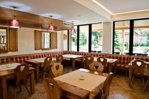 a restaurant with wooden tables and chairs and windows at Domeniul Dornei in Vatra Dornei