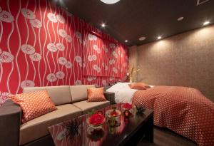 a bedroom with a bed and a couch and a table at Hotel Waraku Shibukawa in Shibukawa