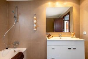 een badkamer met een wastafel, een spiegel en een bad bij Apartamento Castello Playa in Can Picafort