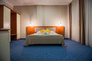 a hotel room with a bed with yellow pillows at Hotel CITY in Prnjavor