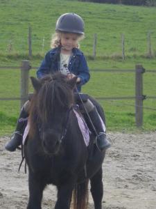 een klein meisje op een zwart paard bij Gîte de campagne Dromard in Sancey-le-Long