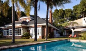 a house with a swimming pool and palm trees at Villa Antumalal B&B in Málaga