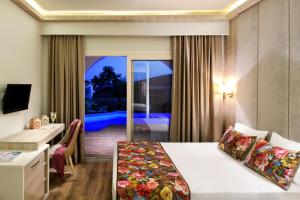 a hotel room with a bed and a desk and a balcony at Alexandra Beach Spa Resort in Potos