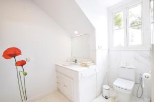 a white bathroom with a toilet and a sink at Villa Antumalal B&B in Málaga