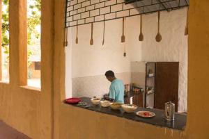Un uomo in piedi in una cucina che prepara il cibo di Kamp Kamouflage Kanha a Kanha