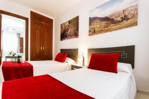 two beds with red pillows in a room at Apartamentos El Tajo & SPA in Ronda