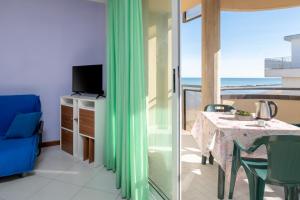 Residence Belvedere Vista في ريميني: غرفة مع طاولة وتلفزيون وشرفة