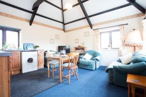 ein Wohnzimmer mit Tisch und Stühlen in der Unterkunft Sharlands Farm Holiday Cottages in Bude