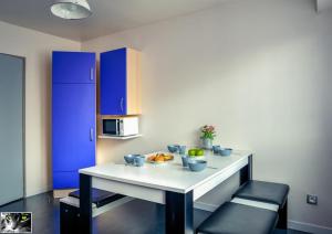 a kitchen with a white table and blue cabinets at Appartement Spacieux Schiltigheim in Schiltigheim +14 photos