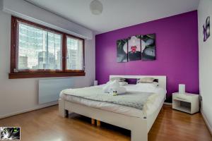 a bedroom with purple walls and a white bed at Appartement Spacieux Schiltigheim in Schiltigheim