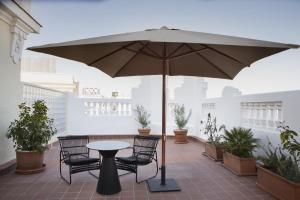 einen Tisch und Stühle unter einem Sonnenschirm auf einer Terrasse in der Unterkunft Petit Palace Triball in Madrid