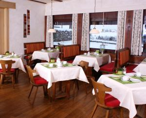 a dining room with white tables and chairs and windows at Berg-Cafe in Kempten