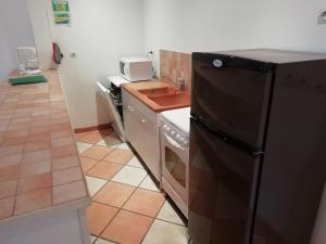 a kitchen with a black refrigerator and a tiled floor at Holiday home with swimming pool in Quend