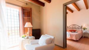 a living room with a white chair and a bed at Mas del Mar in Sant Pere Pescador