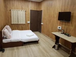 a room with a bed and a desk and a television at Living Green Farms in Allahābād