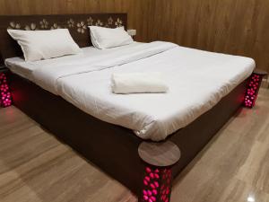 a large bed with white sheets and red lights on it at Living Green Farms in Allahābād