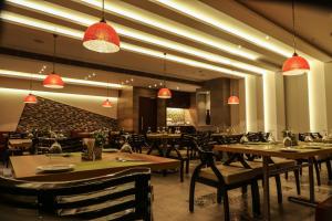 a restaurant with tables and chairs and pendant lights at The Grand Asansol in Āsansol