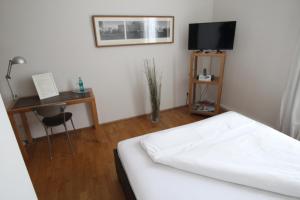 Schlafzimmer mit einem Bett und einem Schreibtisch mit einem TV in der Unterkunft Hotel Lorenz in Essen