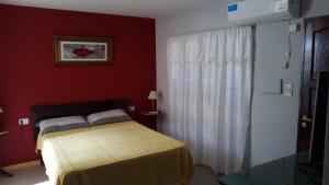 - une chambre avec un lit et un mur rouge dans l'établissement Posadas la hermosa, à Posadas